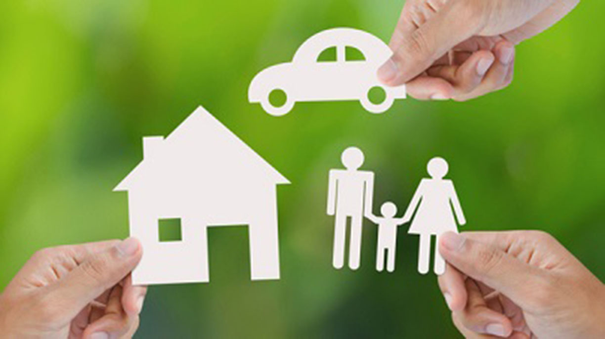 Hand holding a paper home, car, family on green background